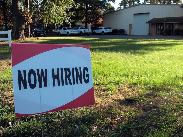 Now Hiring sign posts on a lawn