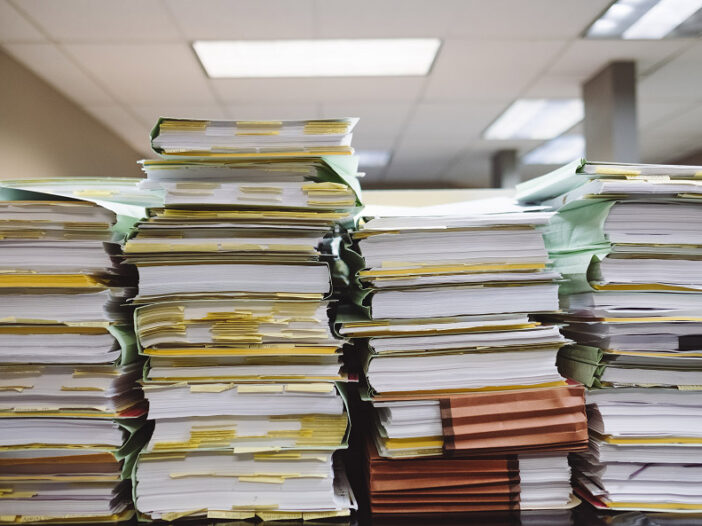 Four stacks of paperwork lined up next to the other.